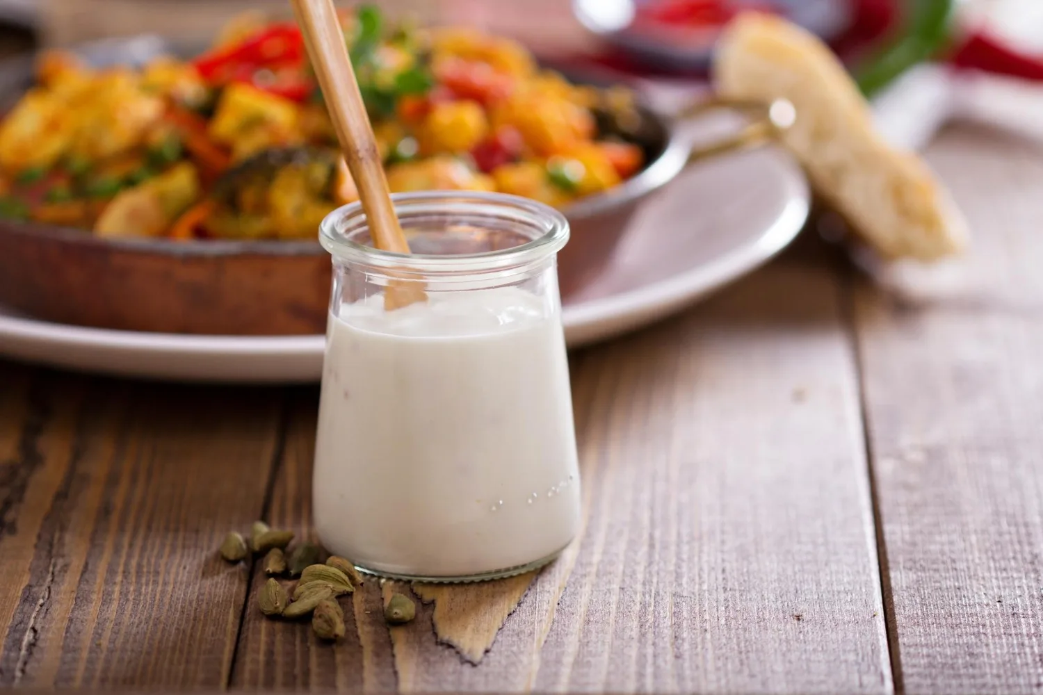 11 beneficios del kéfir: para qué sirve y sus propiedades 6 Vaso de kéfir cremoso con cuchara de madera sobre mesa de madera, bebida probiótica natural